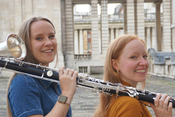 Hannah Shilvock & Viola Lenzi standing outside with bass clarinet on their shoulders